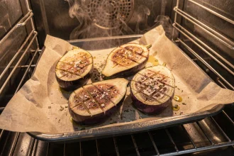 Aubergines coupées en deux sur une plaque de cuisson au four, chair dorée et croustillante, prêtes à être servies